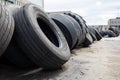 Stack of old used tires of different sizes and types in abandoned scrap yard.