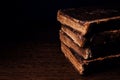 Stack of old worn shabby Jewish books in leather binding in the dark. Closeup. Selective focus. Copy space