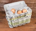 Stack of open pulp egg cartons with several chicken eggs