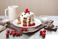 Stack of pancackes with sour cream and fresh berries, mug of tea or tea on dark surface, side view of table decorated with muffins Royalty Free Stock Photo