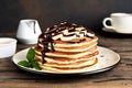 Stack of pancakes with banana and chocolate sauce on wooden brown background Royalty Free Stock Photo