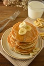 Stack of pancakes with banana slices and honey, on wooden background. Homemade american pancakes, isolated