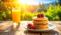 Stack of Pancakes with Berries and Orange Juice in Sunlight displa breakfast Royalty Free Stock Photo