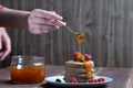 A stack of pancakes with fresh raspberries and blueberries topped with jam on a light plate on a wooden background Royalty Free Stock Photo