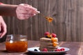 A stack of pancakes with fresh raspberries and blueberries topped with jam on a light plate on a wooden background Royalty Free Stock Photo