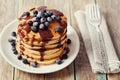 Stack of pancakes or fritters with chocolate sauce and frozen blueberries in a white plate on a wooden rustic table Royalty Free Stock Photo