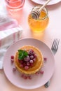 Stack of pancakes with frozen raspberry, red currant and honey on pink background. Selective focus