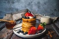 A stack of pancakes with honey, blueberry and strawberry and whip cream on top in plate on wooden table