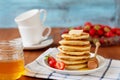 Stack of pancakes with honey syrup, butter and strawberry in a white plate Royalty Free Stock Photo