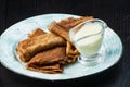 Stack of pancakes on a plate with sour cream. Traditional for the Russian pancake week. Dark background
