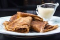 Stack of pancakes on a plate with sour cream. Traditional for the Russian pancake week. Dark background