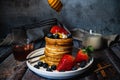 A stack of pancakes with pouring honey, blueberry and strawberry and whip cream on top in plate on wooden table