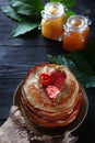 Stack of pancakes with strawberries on a black background. Two jars of honey are next to each other on the table. Vertical photo. Royalty Free Stock Photo