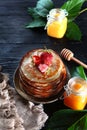 Stack of pancakes with strawberries on a black background. Two jars of honey are next to each other on the table. Vertical photo. Royalty Free Stock Photo