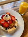 Stack of pancakes with strawberries, blueberries, bananas, and cream with juice Royalty Free Stock Photo