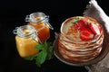 A stack of pancakes with strawberries and mint . Jars of honey on the table. Photo on a black background. Copy of the space. Royalty Free Stock Photo