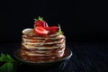 A stack of pancakes with strawberries and mint . Photo on a black background. Copy of the space. Concept of a holiday and still Royalty Free Stock Photo