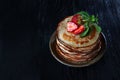 A stack of pancakes with strawberries and mint . Photo on a black background. Copy of the space.Top view Royalty Free Stock Photo