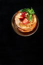 A stack of pancakes with strawberries and mint . Vertical photo on a black background. Copy of the space.Top view Royalty Free Stock Photo