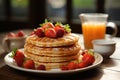 A stack of pancakes with strawberries on a plate and orange juice