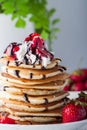 Stack of pancakes with strawberries, whip cream and chocolate syrup on a white plate on a white background. Royalty Free Stock Photo