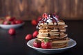 Stack of pancakes with strawberries, whip cream and chocolate syrup on a white plate on a wooden background. Royalty Free Stock Photo