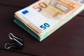 Stack of paper euro banknotes and stationery clip on wooden table. Heap of money. Selective focus