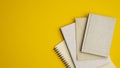 Stack of paper notebooks on yellow background. Flat lay, top view school of office supplies