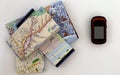 A stack of paper travel maps and an electronic satellite navigator