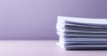 A stack of papers on a table, with the background blurred out in purple hues Royalty Free Stock Photo