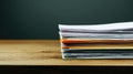 Stack of papers on wooden surface against dark background Royalty Free Stock Photo