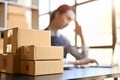 Stack of parcel boxes on the table over blurred background of a female using laptop