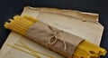 A stack of pasta wrapped in kraft paper on a table with aged sheets of paper.