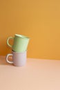 Stack of pastel color mug cup on pink table. orange wall background Royalty Free Stock Photo