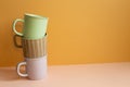 Stack of pastel color mug cup on pink table. orange wall background Royalty Free Stock Photo