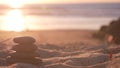 Stack of pebble stones, sandy ocean beach, sunset sky. Rock balancing by water. Royalty Free Stock Photo