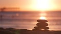 Stack of pebble stones, sandy ocean beach, sunset sky. Rock balancing by water. Royalty Free Stock Photo