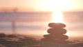 Stack of pebble stones, sandy ocean beach, sunset sky. Rock balancing by water. Royalty Free Stock Photo