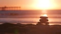 Stack of pebble stones, sandy ocean beach, sunset sky. Rock balancing by water. Royalty Free Stock Photo