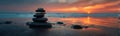 Stack of pebbles balancing on wet sand with beautiful sunset reflecting on the water Royalty Free Stock Photo