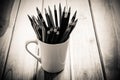 Stack of pencils in a glass on wooden background,tone sepia. Royalty Free Stock Photo