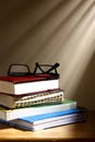 Stack or pile of books and eyeglasses on a wooden table Royalty Free Stock Photo