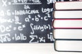 Stack and pile of books in front of a blackboard in school.