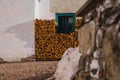 Stack or pile of fire wood lying next to a house rising up to the picturesque window frame in green color Royalty Free Stock Photo