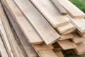 A stack of pine new boards lies in a pile of building materials