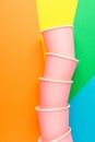 Stack of pink paper drinking cups on multicolored pinwheel background. Funky retro style. Birthday party fest celebration kids fun