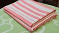 a stack of pink and white towels on top of a green table cloth on a table with a wooden chair in the background and a wooden Royalty Free Stock Photo