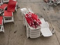 Stack of plastic chaise lounge with closed sunshades on wet sea side cement beach top view Royalty Free Stock Photo