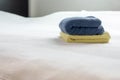 Stack of plush hotel clean soft towels White,Blue,Yellow towel on bed decoration in bedroom interior