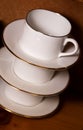 Stack of porcelain coffee cups with gold rim on wooden background